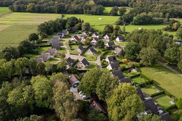 Droneshot van vakantiepark Posterbos met de vakantiehuisje omgeven door groene natuur