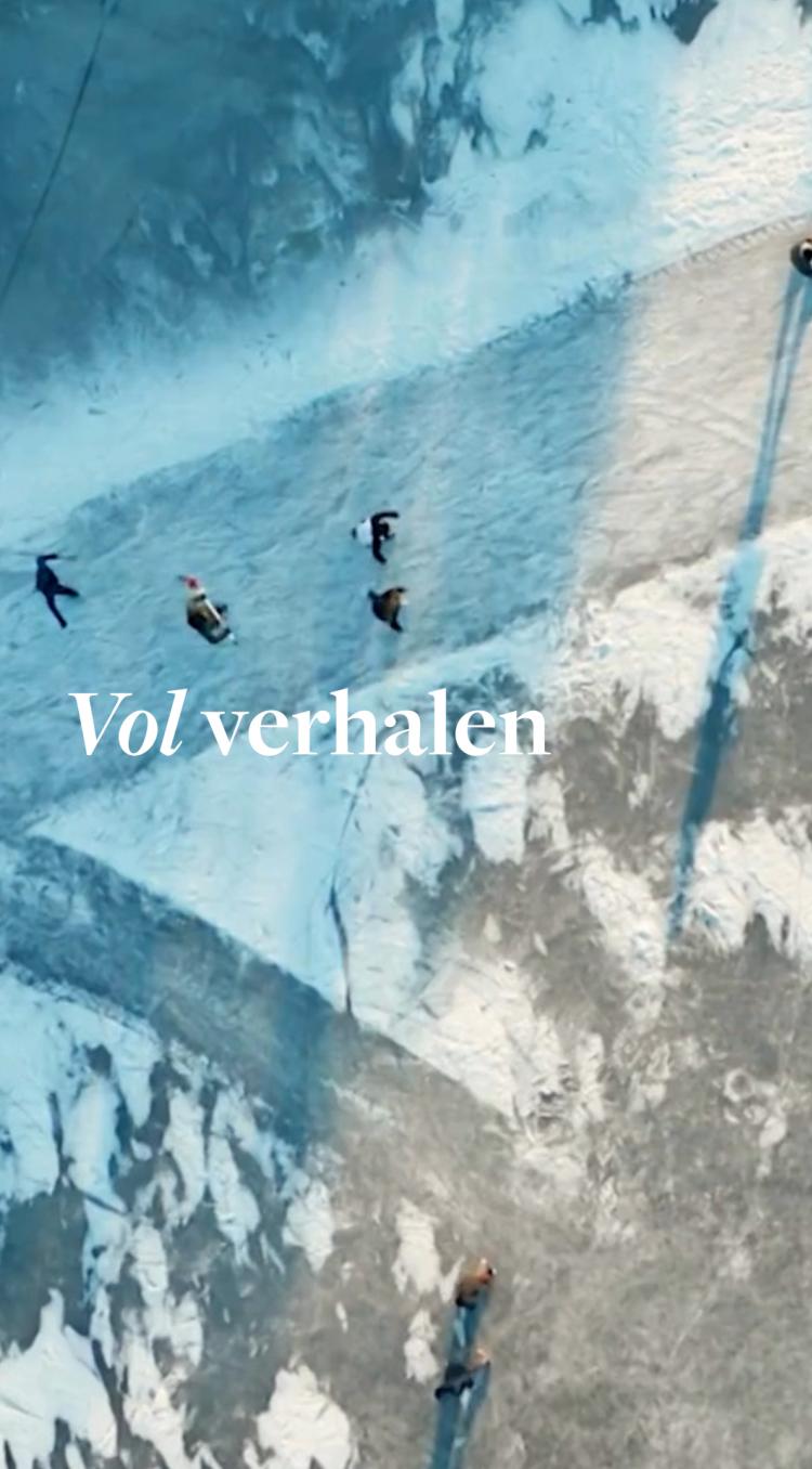 Een bevroren landschap van bovenaf met mensen die schaatsen op het ijs en lange schaduwen werpen in het winterlicht.